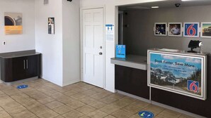 A reception area with a counter, a door, and informational posters. - Motel 6 Paris, TX (Paris)