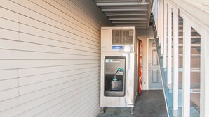 An ice dispenser mounted on a wall next to a door. - Motel 6 Paris, TX (Paris)