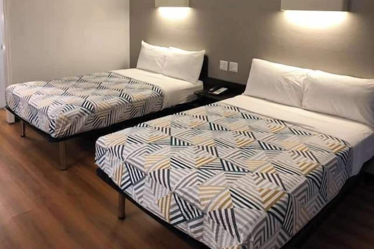 Two twin beds with patterned bedding in a hotel room.