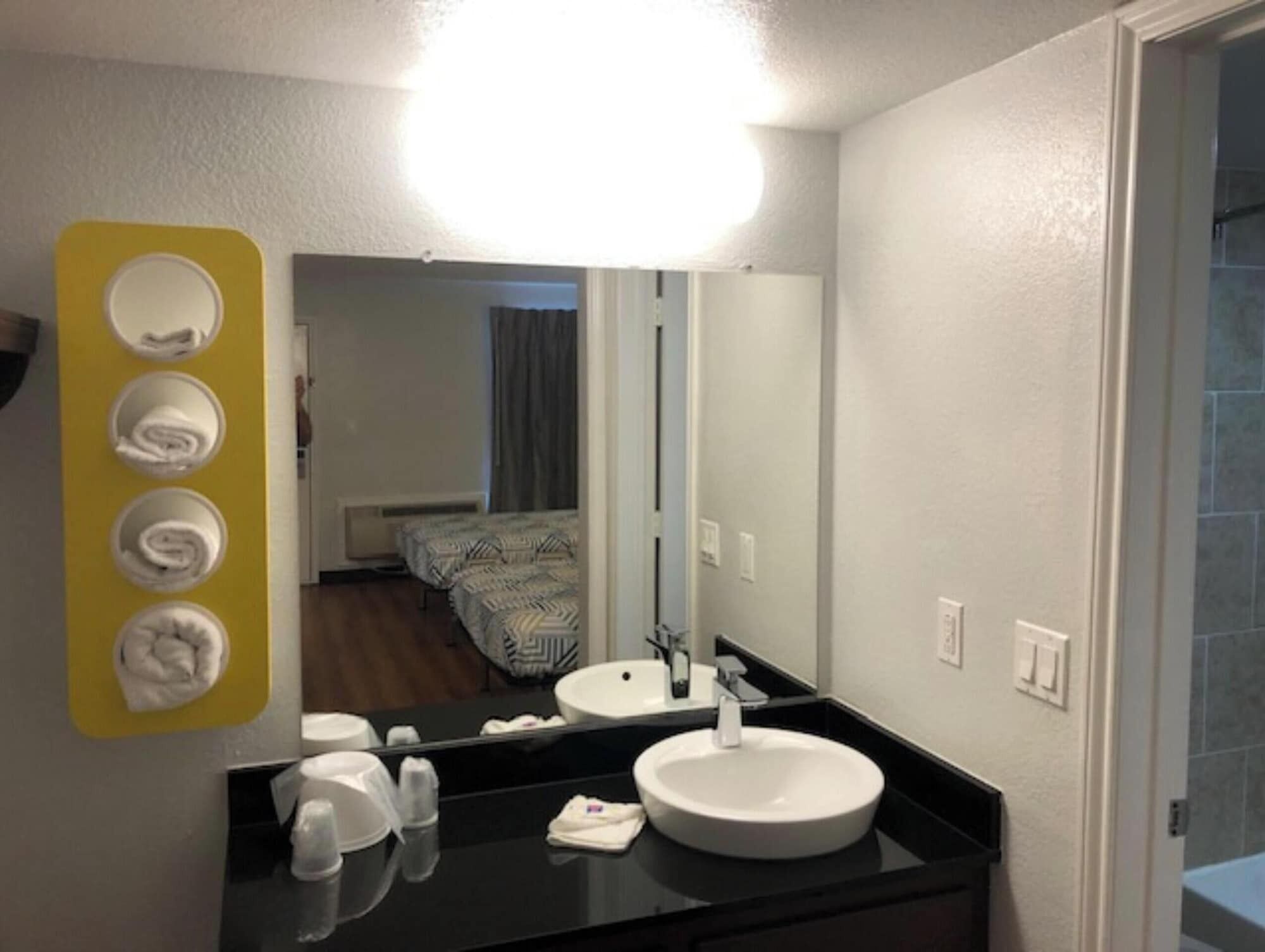 Une salle de bain d’hôtel avec un grand miroir, deux lavabos et un distributeur de serviettes.