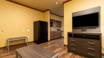 A modern kitchen with a built-in microwave, a black refrigerator, and a flat-screen TV mounted on a wooden cabinet.