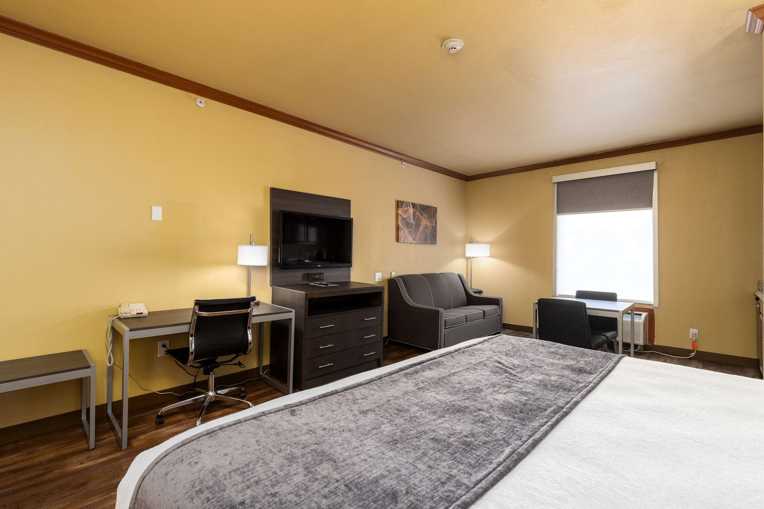 Een hotelkamer met een bed, een bureau, een stoel, een televisie en een raam.