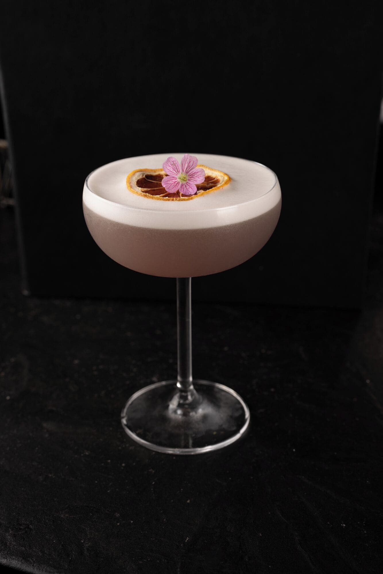 A round table with a white surface and a single pink flower on top.