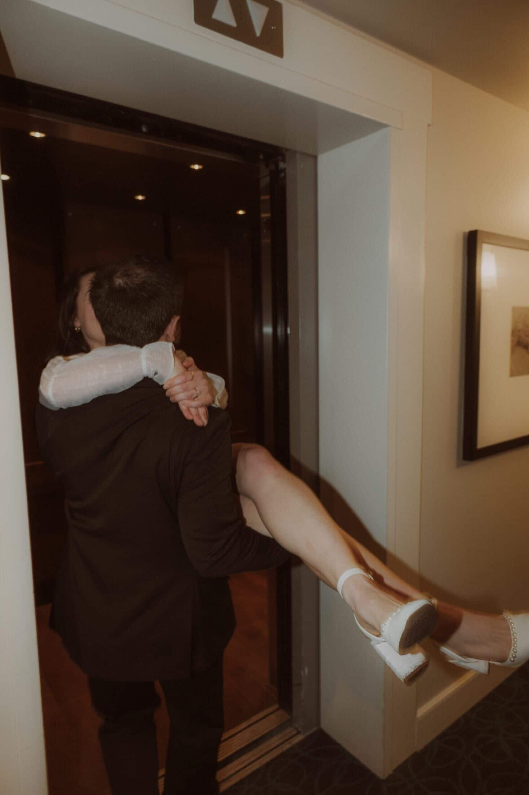 A man carrying a woman in an elevator.
