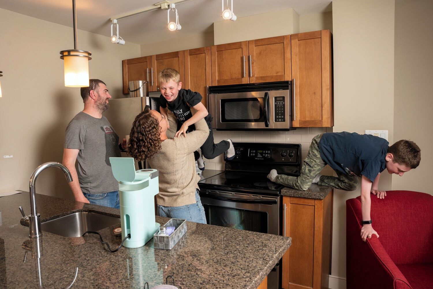 A modern kitchen with wooden cabinets, stainless steel appliances, and a granite countertop.