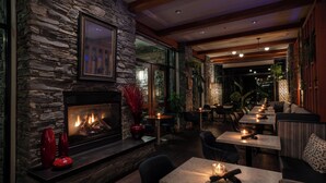 Een gezellig restaurant met stenen muren, een open haard en tafels met kaarsen.
