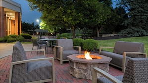 An outdoor seating area with wicker chairs and a stone fire pit.