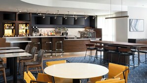 A modern hotel lobby with a bar area, seating arrangements, and a large screen.