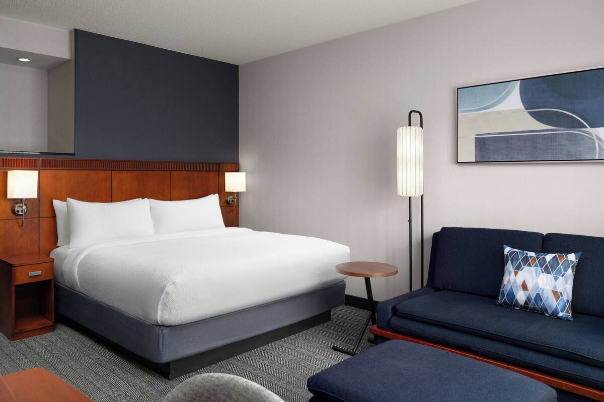 Ein Hotelzimmer mit einem großen Bett, einer Couch, einem kleinen Tisch und einer Lampe.