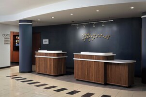 A reception area with two wooden reception desks, a wall-mounted sign reading 'MARRIOTT BONVOY,' and a 'CRATE' sign indicating amenities.