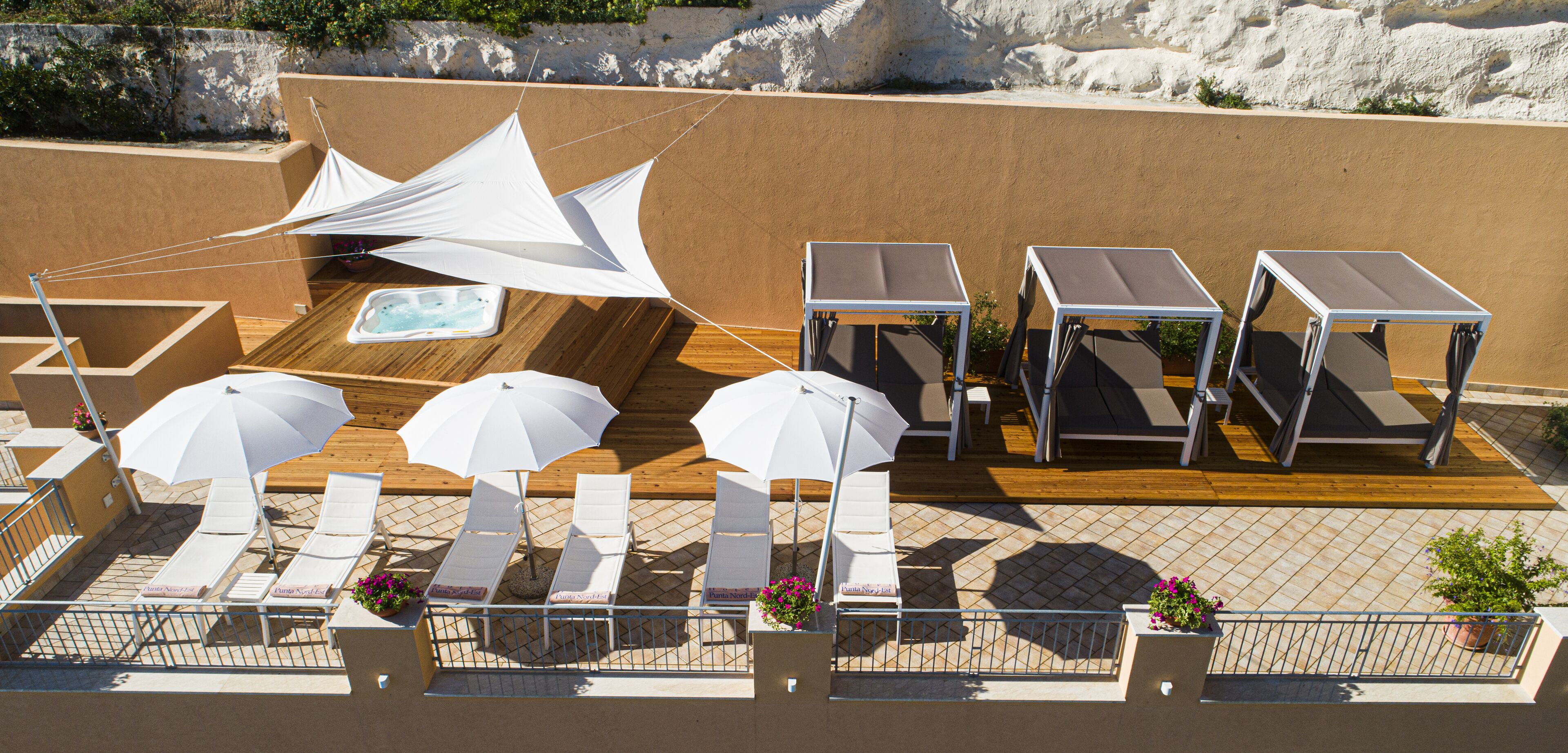 A rooftop terrace with sun loungers, umbrellas, and a pool table.