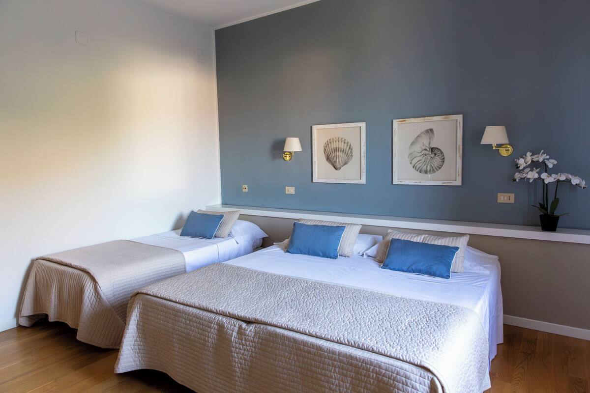 Habitación de hotel con dos camas, una pared azul y decoración en la pared.
