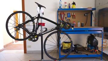 Una bicicleta sujeta a un soporte en una habitación con un panel de usos múltiples y un banco de trabajo azul.
