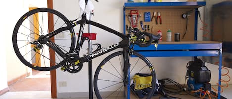 A bicycle mounted on a stand in a room with a pegboard wall and a blue workbench.
