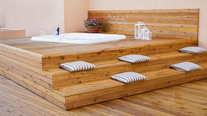 A wooden spa area with a hot tub, steps, and a bench.