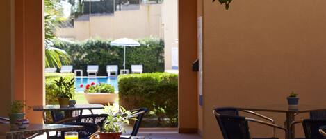 An outdoor dining area with tables, chairs, and potted plants.