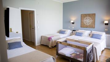 A hotel room with two beds, a crib, and a wall-mounted compass decoration.