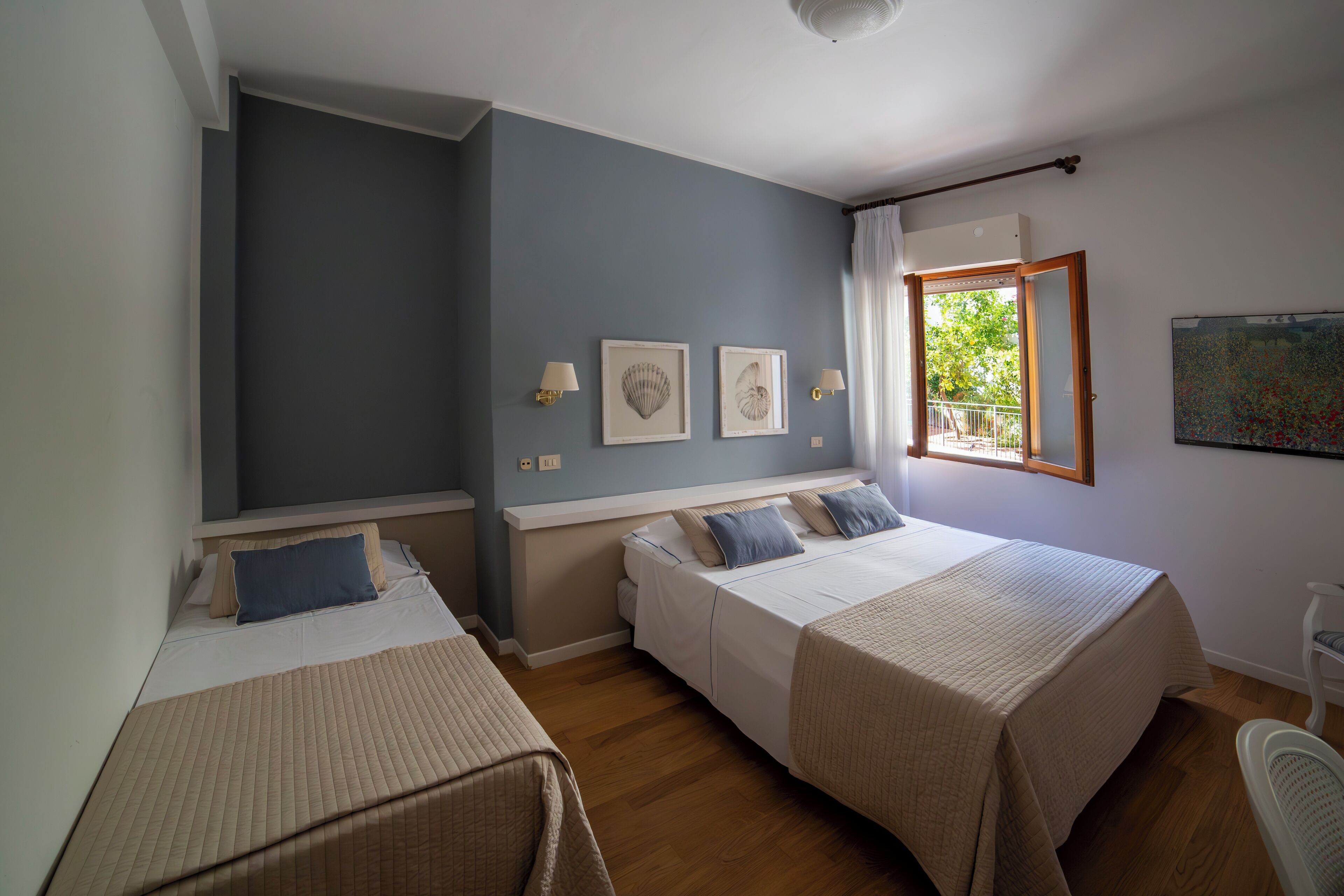 Une chambre avec deux lits, une fenêtre avec des rideaux et des lampes fixées au mur.