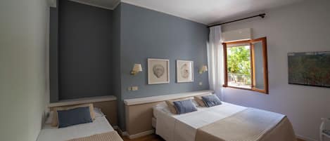 Un dormitorio con dos camas, una ventana con cortinas y lámparas fijadas a la pared.