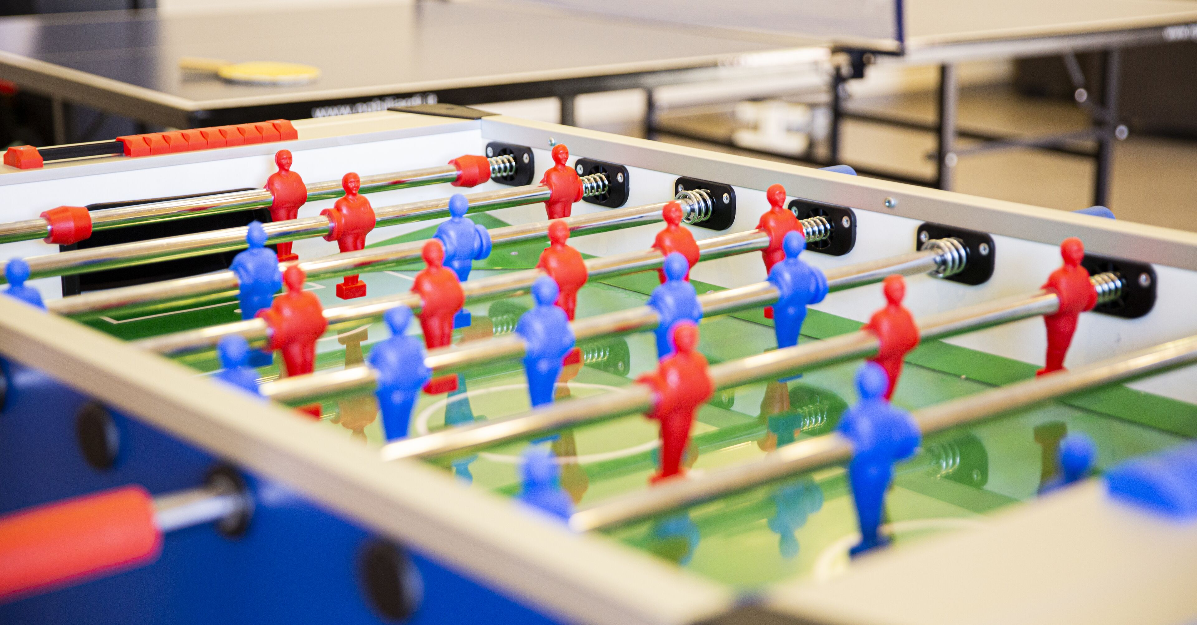 Una mesa de fútbolín con figuras de jugadores rojos y azules.