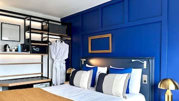 A modern hotel room with a large bed, a built-in wardrobe, and a bedside table with a lamp.