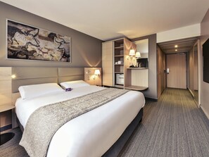 A hotel room with a large bed, a nightstand, a wall-mounted lamp, a mirror, and a painting. - Mercure Périgueux Centre (Périgueux)