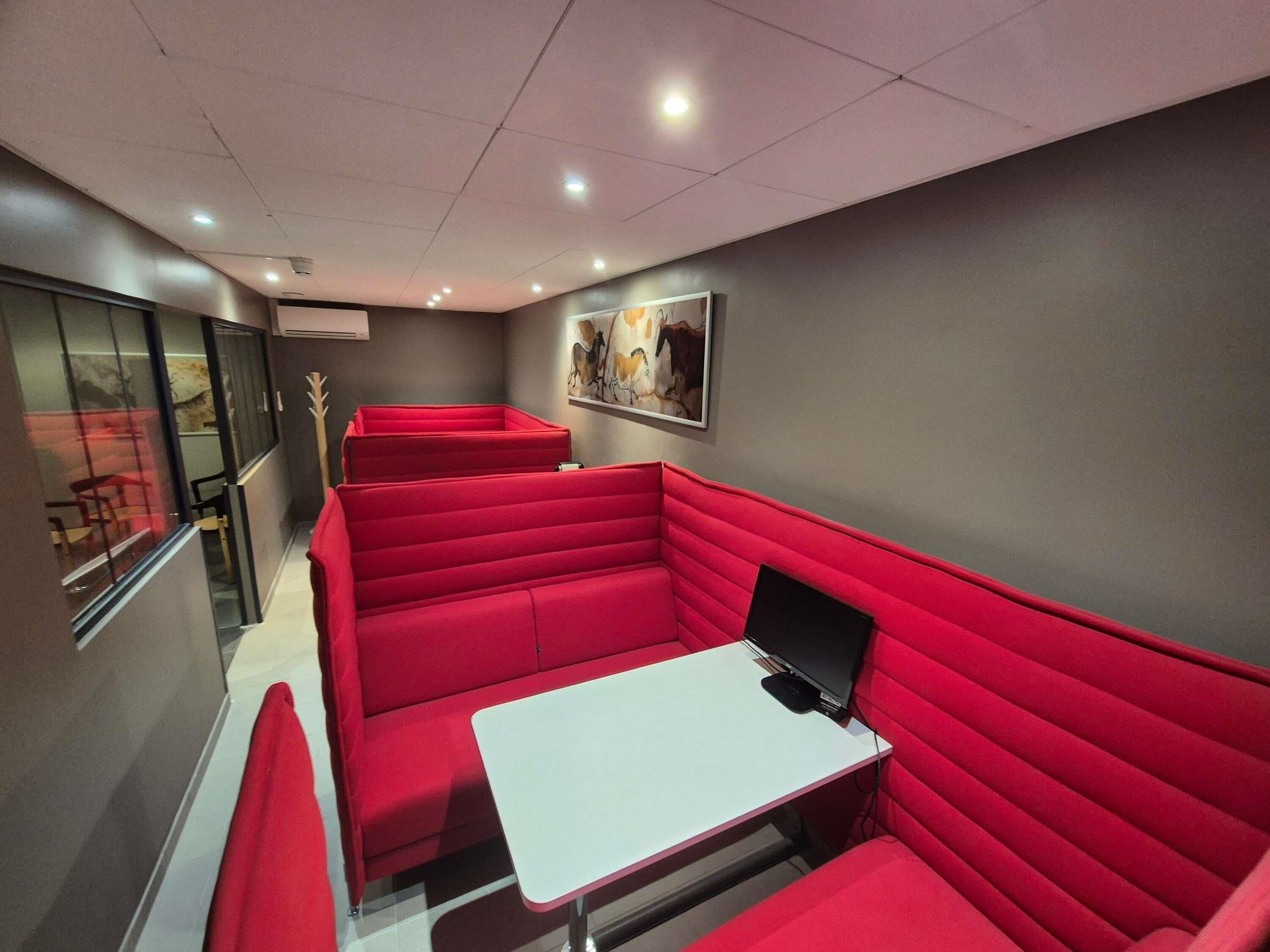 Un restaurante con asientos rojos, una mesa blanca y un cuadro en la pared.