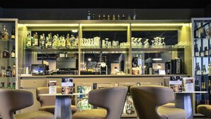A bar area with seating, a bar counter, and shelves stocked with bottles and glasses. - Mercure Périgueux Centre (Périgueux)