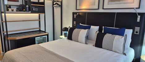 A modern hotel room with a bunk bed, a desk with a computer, and a bedside table.