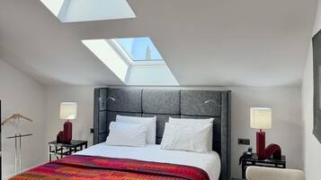 Une chambre d’hôtel moderne avec un grand lit, des fenêtres de toit et une vue sur une tour.