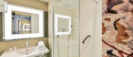 A modern bathroom with a glass-enclosed shower, a white sink, and a large mirror.