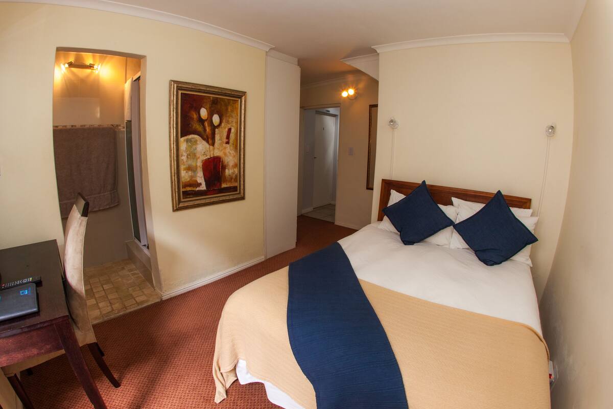 Une chambre d’hôtel avec un lit, un bureau et un tableau au mur.