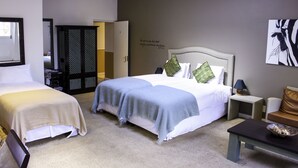 Ein Hotelzimmer mit zwei Betten, einem kleinen Tisch, einem Nachttisch und einer Wand mit einem Zitat.