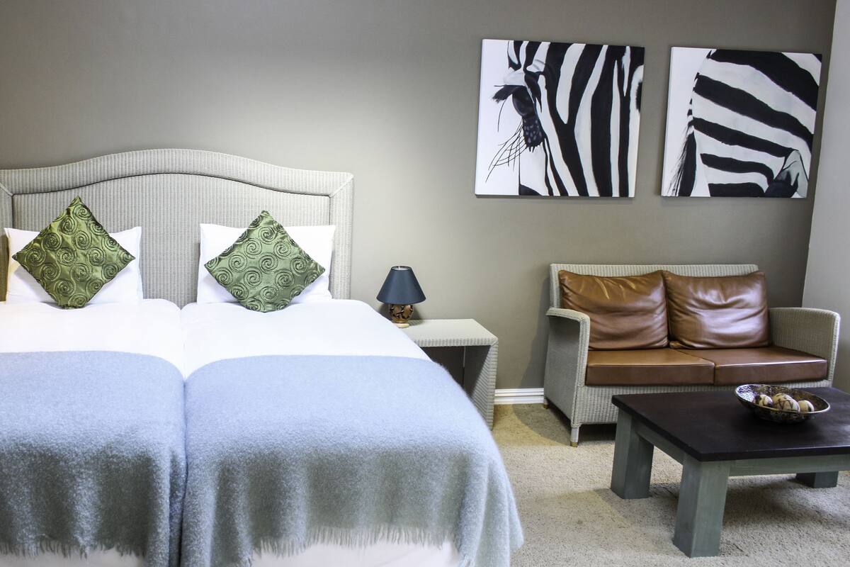 Une chambre bien rangée, avec un lit, deux tables de chevet, un canapé et une table basse.