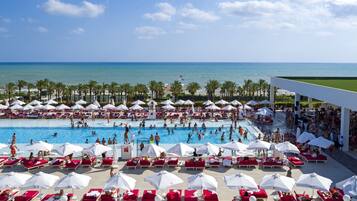Relax by the pool surrounded by sun loungers and umbrellas, with a scenic ocean view.