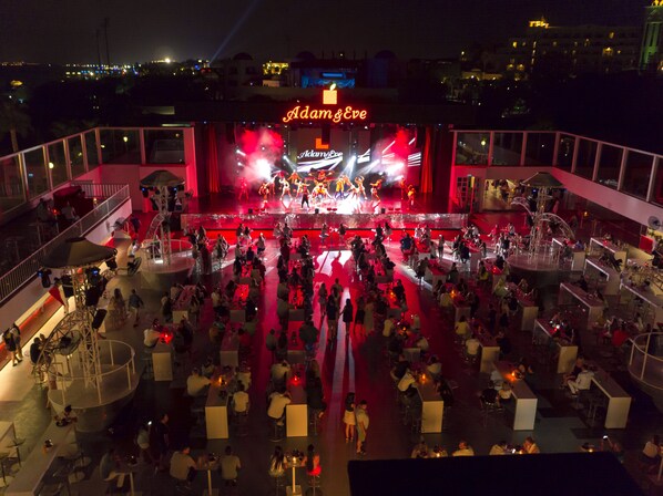 A venue with a stage and audience seating, featuring a prominent 'Adam & Eve' sign.
