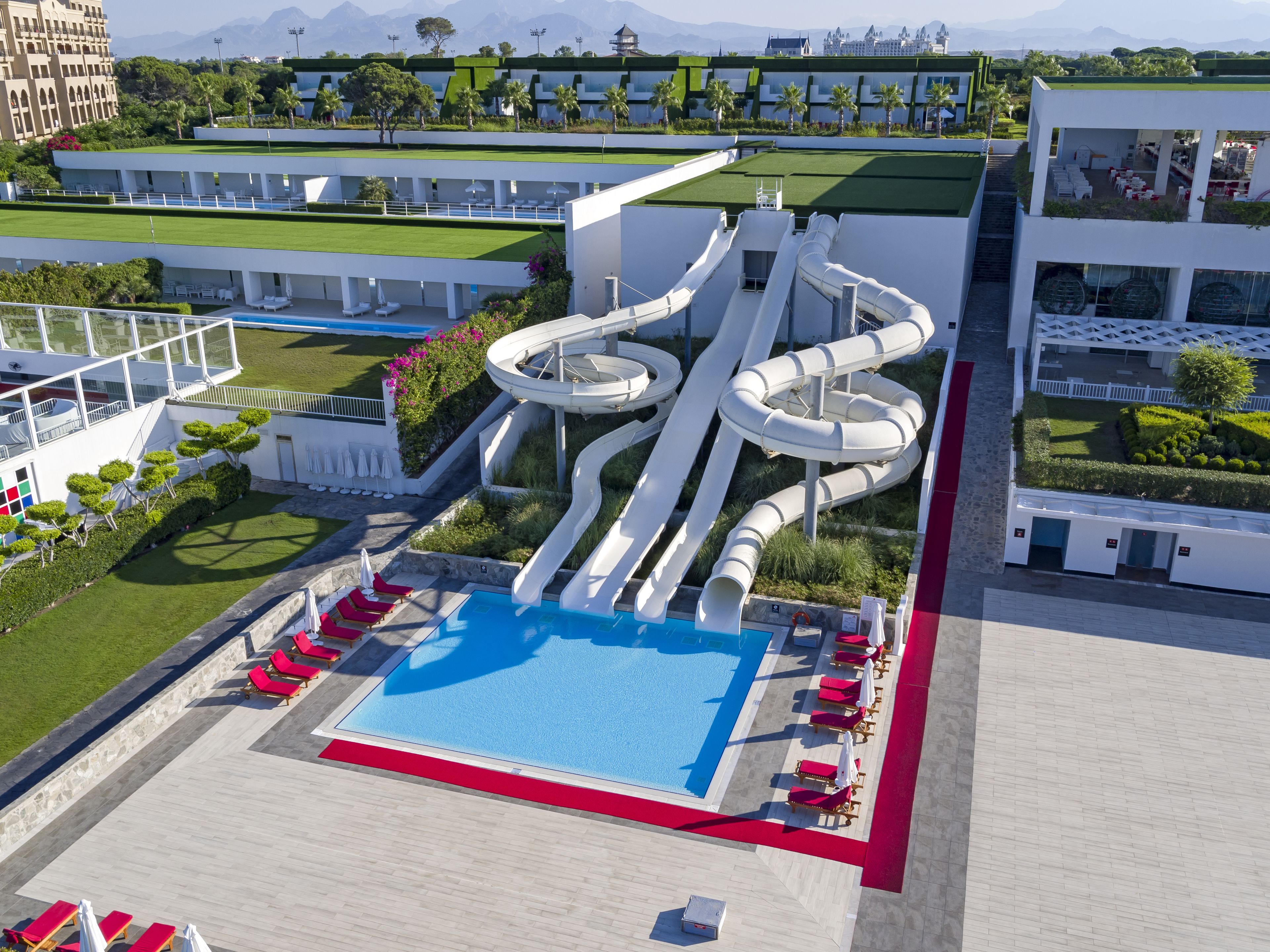 A modern resort with a large pool, multiple slides, and sun loungers.