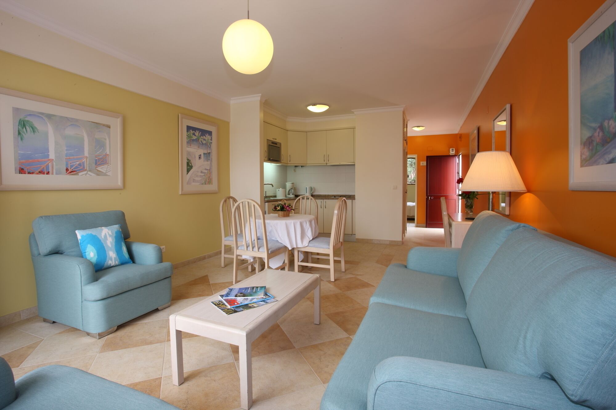A living room with a sofa, a coffee table, and a dining area with chairs and a table.