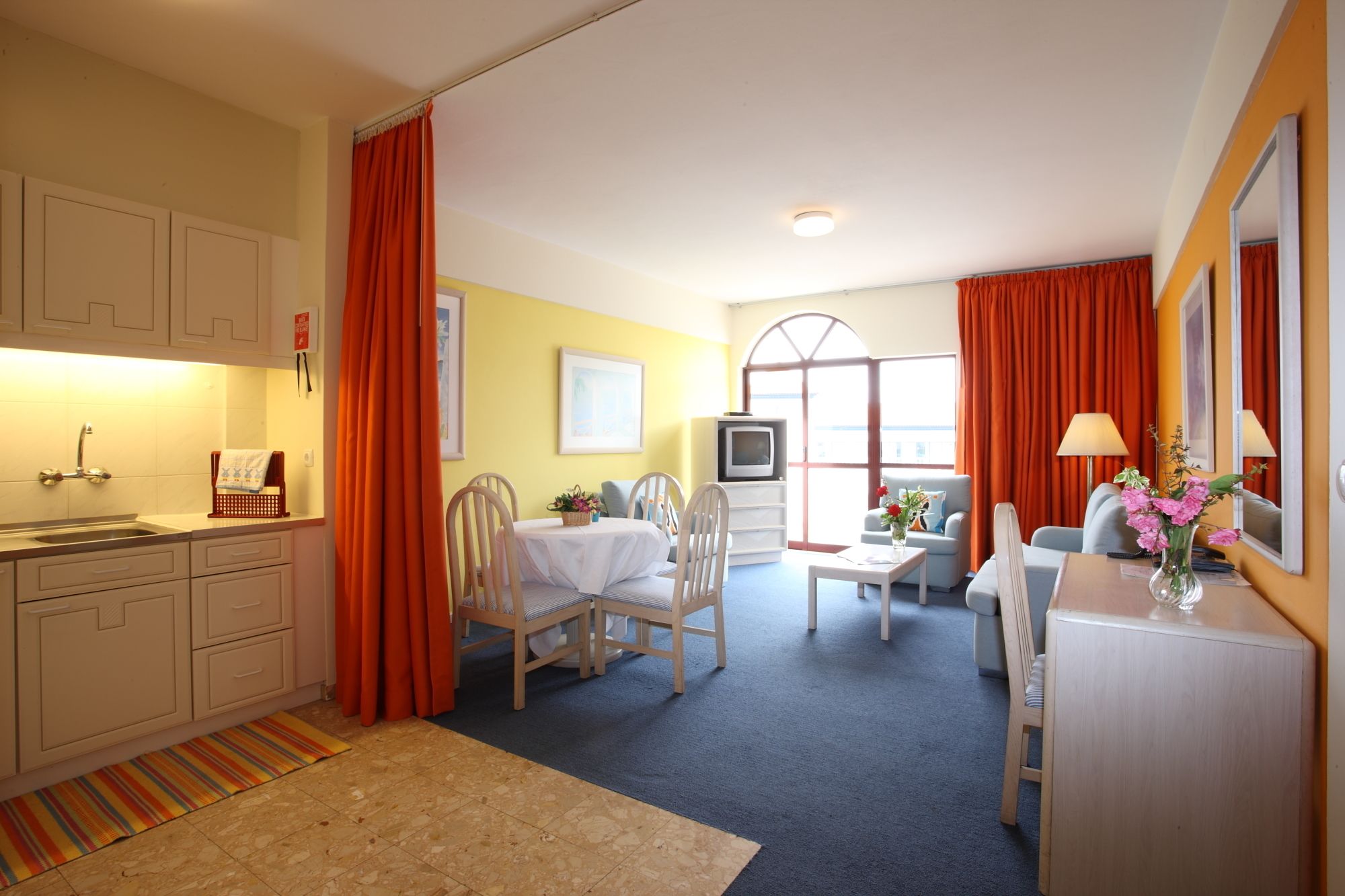 Habitación de hotel con kitchenette, zona de comedor, televisor y área de estar con vistas.