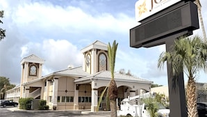 A hotel with a prominent sign, a central tower, and a covered entrance area. - JC Inn (Clermont)