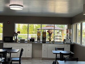 A kitchen with white cabinets, a microwave, a coffee machine, and a window with a view of a gazebo.