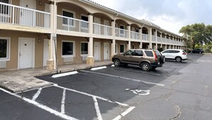 Un hotel de varios pisos con balcones, un estacionamiento y un cielo despejado.