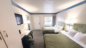 Una habitación de hotel con dos camas, un escritorio con silla, un televisor y una puerta.