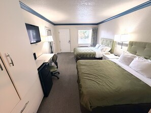 Une chambre d’hôtel avec deux lits, un bureau avec une chaise, une télévision et une porte.