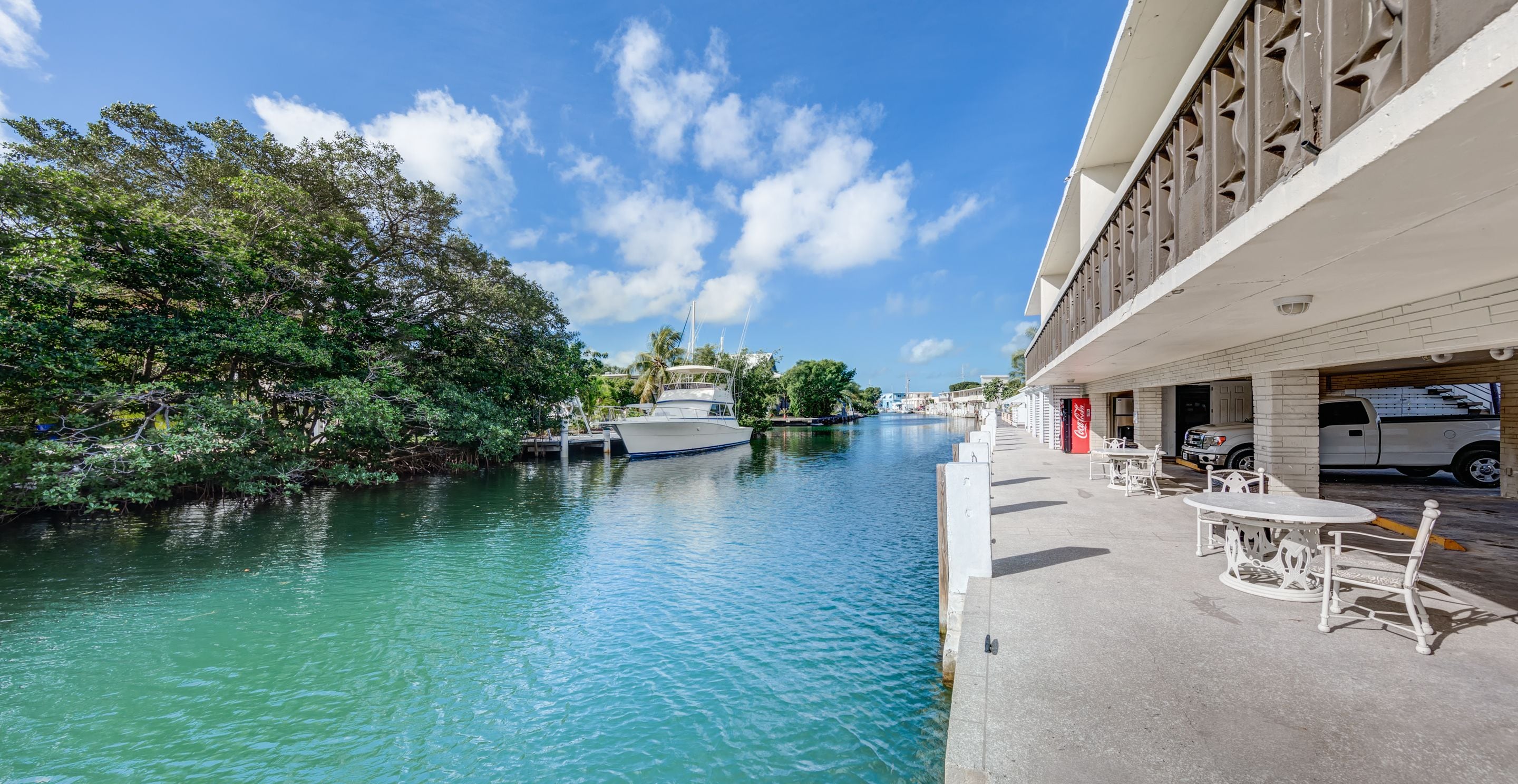A waterfront hotel with a dock, a boat, and outdoor seating by the water.