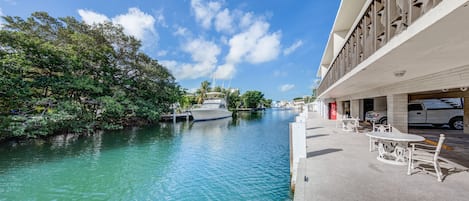 A waterfront hotel with a dock, a boat, and outdoor seating by the water.