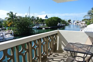 A balcony with a view of a marina, featuring boats and palm trees. - Creekside Inn (Tavernier)