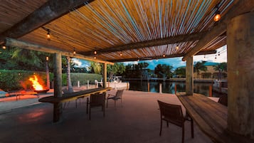 An outdoor patio with a fire feature, seating, and a view of a canal.