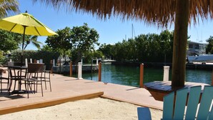 A waterfront patio with outdoor seating, a yellow umbrella, and a view of the water. - Creekside Inn (Tavernier)