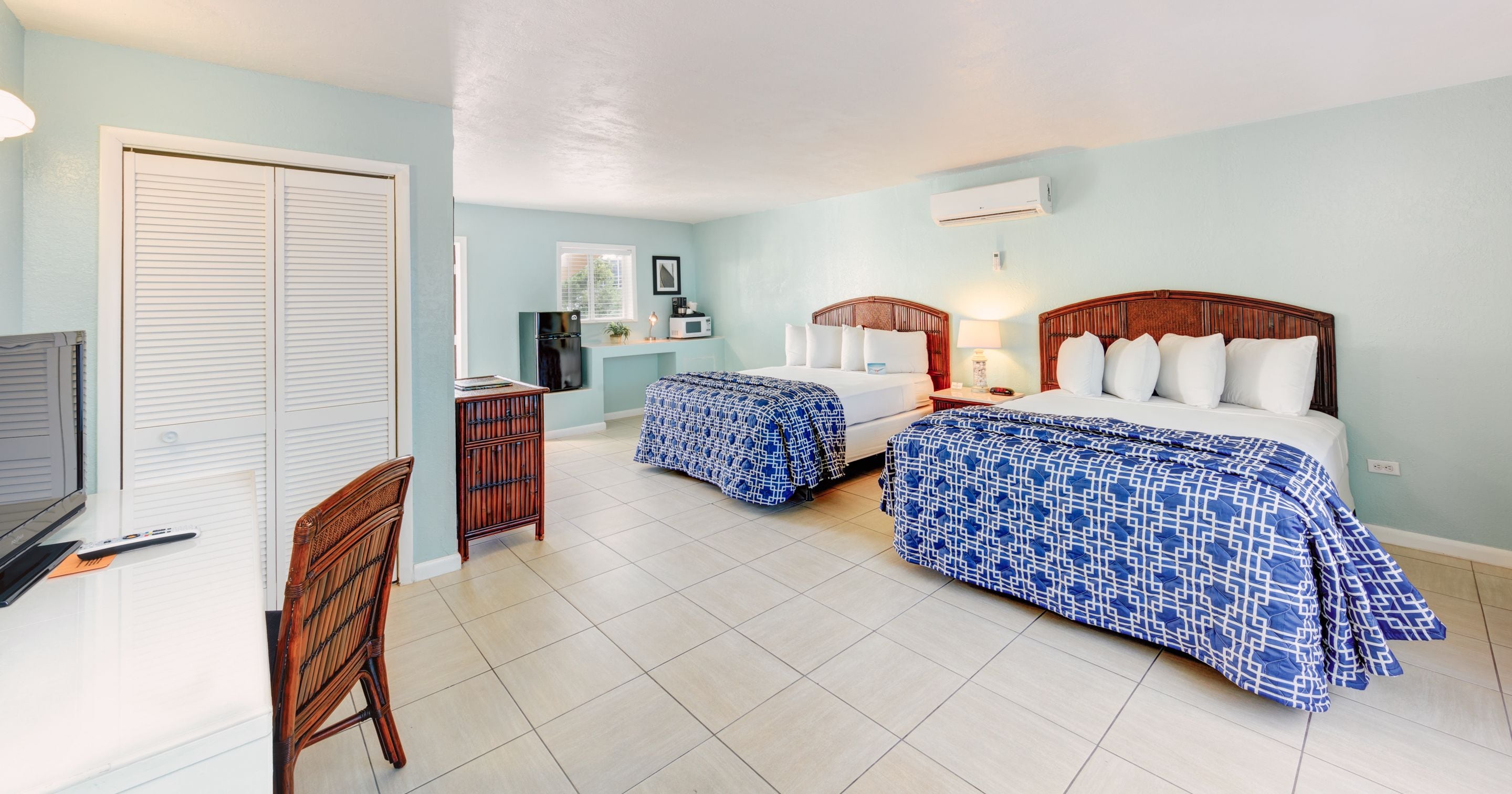 A hotel room with two beds, a desk, a television, and a wardrobe.